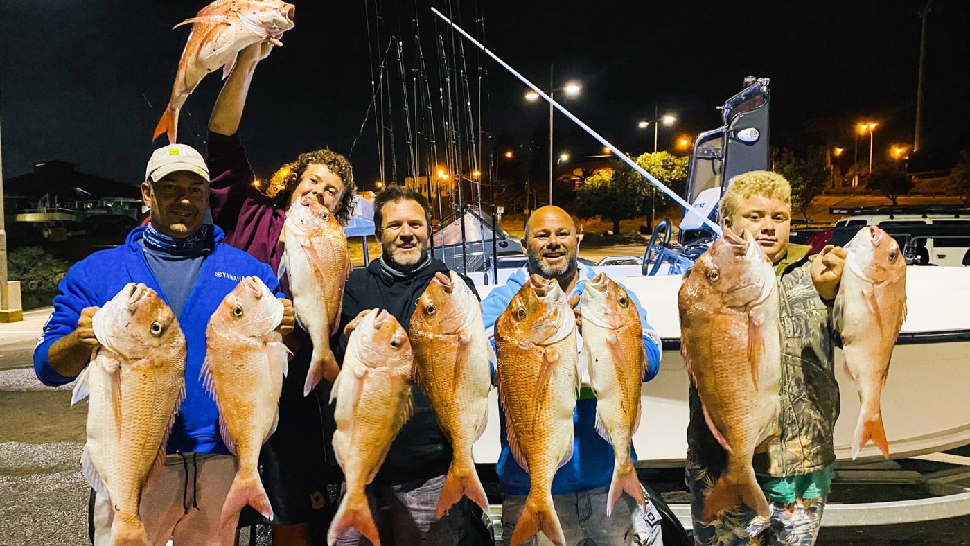 Crew with bag of snapper at Frankston boat ramp at night